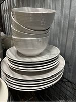 Stacked white ceramic bowls and plates with ridged exterior and ring pattern on plates