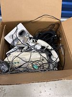 Open cardboard box showing multiple Panasonic telephones, phone bases, cords, and power adapters tangled inside.