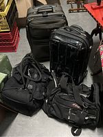 Four travel bags including two soft duffel bags and two rolling suitcases on floor.