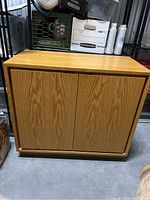 Closed wooden Mid-Century Modern cabinet with three vertical panels on the front doors showing wood grain and light scratches on surface.