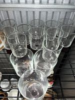 Top angle view showing all 10 clear glasses with smoked bases arranged on metal shelving.