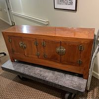Front view of Oriental wooden cabinet with four doors featuring round metal hardware and a warm brown finish, showing scratches on surface.