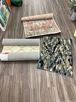 Three synthetic accent rugs placed on hardwood floor showing different patterns and colors