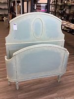 Full view of twin size antique bed frame headboard and footboard painted light blue with shabby chic finish.