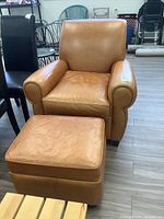 Front view of tan leather armchair with matching ottoman