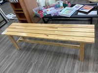 Full side view of the pine bench showing the slat top and supporting legs with horizontal beam.