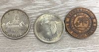 Three Canadian commemorative coins laid out side by side: 1955 silver dollar with canoe design, 1967 silver dollar with flying loon design, and a commemorative one cent coin with Prince Edward Island tree design.