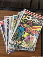 Photo of 10 assorted comic books standing upright in protective sleeves; front of the top comic shows Marvel Comics Greatest cover featuring The Fantastic Four.