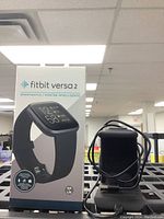 Front view of Fitbit Versa 2 box with image of smartwatch and charging dock.