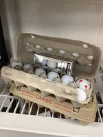 Top and side view of 4 egg cartons containing golf balls, one carton missing 2 balls, some logos visible on balls.