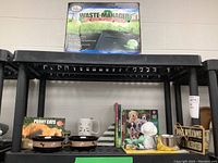 Overall lot shown on black shelving with larger items on top and smaller items on lower shelves