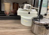 Overview of the kitchen items including pots, ricer, plastic storage containers, measuring cups, and plastic juice jugs arranged on tabletop.