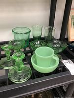 Full lot overview showing jadeite cup and bowl, depression glass dishes, and candlestick holders