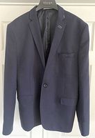 Front view of navy blue Raf Simons men's blazer hanging on hanger, showing overall condition and structure.