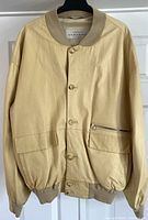 Full front view showing button closure, flap pockets, zippered pocket and ribbed collar and hem