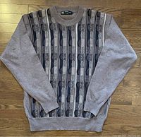 Full view of vintage men's Sergio Louis Italy sweater laid flat on wooden surface showing patterned front panel and solid sleeves.