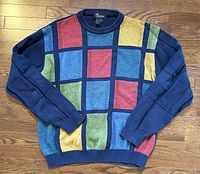 Full front view of the men's Tosani sweater showing the distinct colorful geometric block pattern with navy sleeves and ribbed neckline and hem.