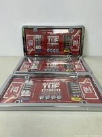Three new sealed Ultimate TUF Combo license plate covers in packaging, showing chrome or stainless steel covers with locking mechanisms and hardware included.