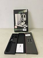 Photo showing the smart watch with black band displayed in an open box, cables and instructions included.