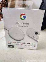 Front view of sealed Google Chromecast with Google TV 4K box showing device and remote images, logos of streaming services like YouTube, Netflix, Prime Video, Disney+, Apple TV