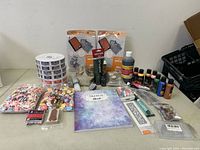 Full view of all crafting supplies including paints, embossing folders, raffle tickets, sketchbook, and embellishments