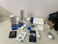 Wide shot showing all items in the lot including travel adapters, GPS positioners, plugs, lights, and batteries.