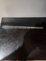 Full view of the 18 inch silver necklace on dark surface, showing chain length and link pattern.