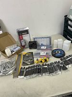 Overview of the tool lot contents showing various boxed items, bags of small hardware, and tool bits.