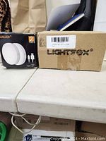 Box of new Lightfox ATV lights on white surface.