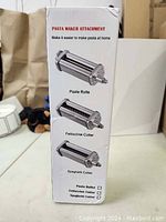 Box packaging showing images and descriptions of pasta roller, fettuccine cutter, and spaghetti cutter attachments for a stand mixer pasta maker.