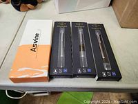 Photo of four boxed pens on table: one Asvine boxed pen and three Parker ballpoint pens in black retail packaging.