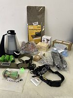 Full overview of lot items including cat scratching pad, bark control collar, harnesses, pet water bottle, toys and nail clippers.