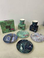 Four decorative plates and two cups with packaging displayed on table