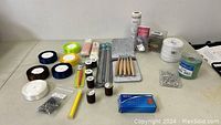 Wide view showing spools of thread, crochet hooks, knitting needles, ribbons, pins, elastic band, and other sewing and knitting supplies on table.
