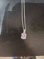 Close-up photo of the oval stone pendant on sterling silver chain necklace on black background.