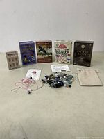 Full lot with five oracle card decks, assortment of polished stones, pink necklace with skull charm, and beige drawstring pouch on a plain surface.