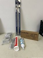 View of chain cleaning tool in box, two caulk tubes, and two double-ended brushes