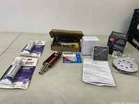Overview of lot showing multiple tools, adhesive sealant, boxed thermostat, sanding disc, and paperwork