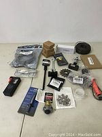 Overview of tool lot with assorted tools, accessories, and new parts laid on table