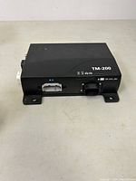 Front and top view showing TM-200 marking, status icons and main 12V power connector.