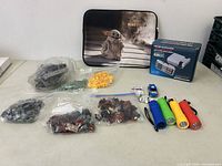 Photo of the lot showing the Mandalorian carrying case, assorted Lego pieces in clear plastic bags, toy cars, light sticks, and the boxed mini NES console.