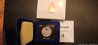 Photo shows 1973 Canadian dollar coin commemorating PEI Centennial in original blue velvet presentation case with yellow cushion backing and outer white box with Canadian crest.