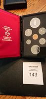 Black case open showing coins including large silver dollar and various smaller Canadian coins, red lining with Royal Canadian Mint logo