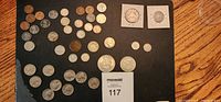 Photo showing an assortment of about 43 older US and Canadian coins laid out on a dark flat surface with a MaxSold tag.