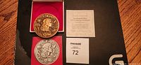 Gold and silver Franklin Mint 1977 Annual Calendar Art Medals in red presentation cases alongside certificate of authenticity and maxsold lot number card.