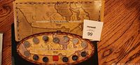 Photo of the Millennium Canada 1999 coin set showing an oval wooden display case containing multiple coins and a map of Canada in the background.