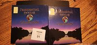 Two blue themed folders labeled 'Presidential Dollar Collection' containing the coin sets side by side.