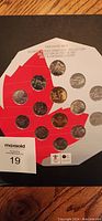 Coins arranged on a white backing card with a red maple leaf design, labeled as Vancouver 2010 Olympic Winter Games Coin Collection in mint condition.