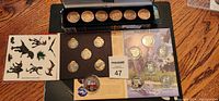 Photo showing multiple sets of collectible medallions including Peanuts 50th Anniversary, animal skins golf game coins, Jurassic Park medallions and endangered species coin set.
