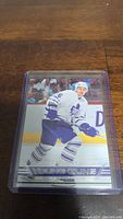 Front view of Brendan Bell YoungGuns rookie card in a protective plastic sleeve showing the player on ice in Toronto Maple Leafs uniform.